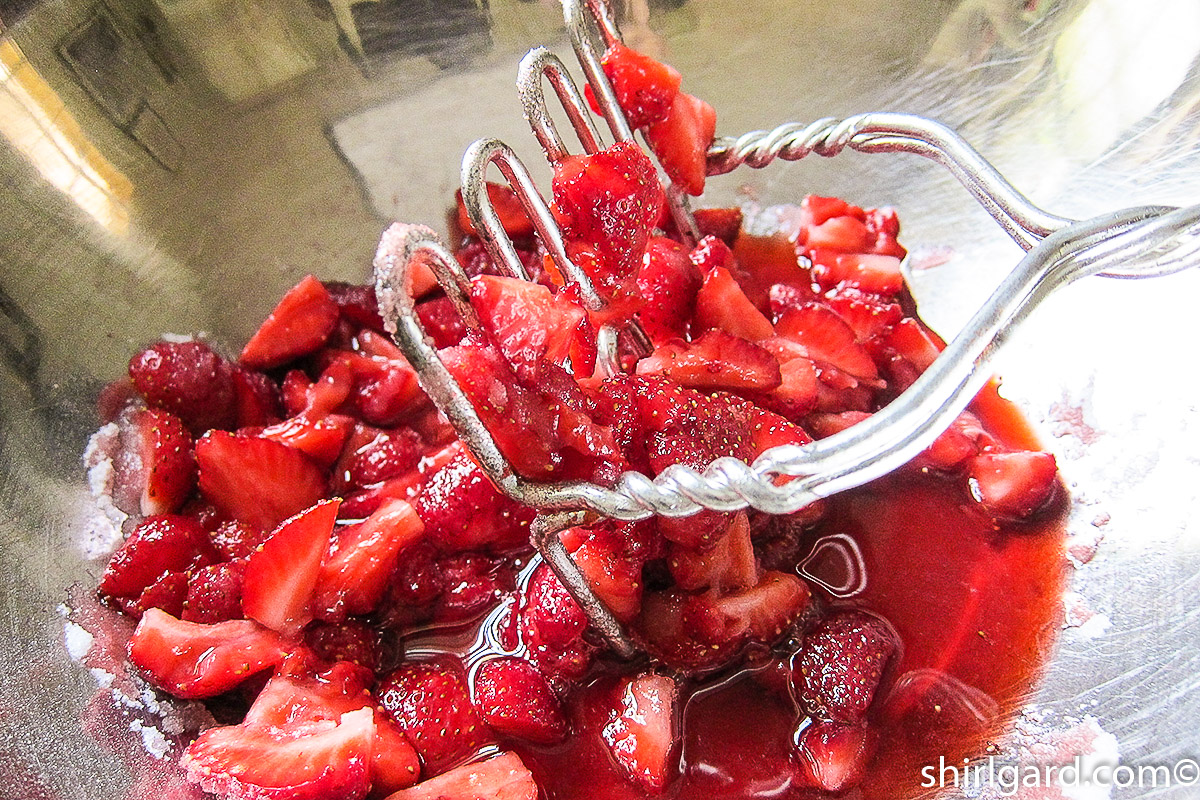 Crushing strawberries & sugar with a potato masher